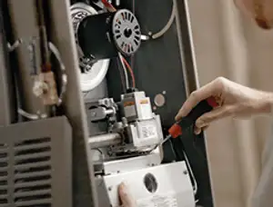 Furnace repair technician inspecting internal components and wiring in Bradenton, FL