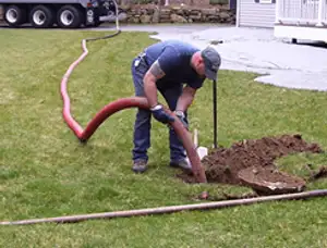 Septic pumping technician servicing a residential septic tank with a vacuum hose in Bradenton, FL