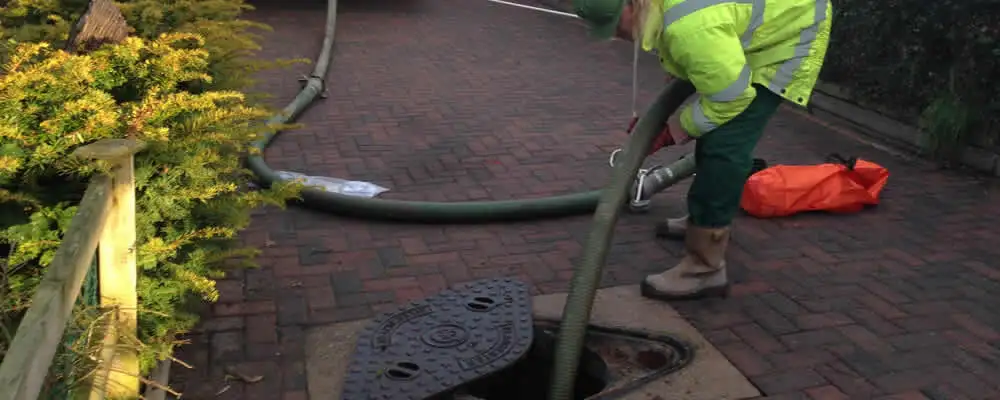 Septic tank cleaning technician servicing a septic tank with a vacuum hose in Bradenton, FL