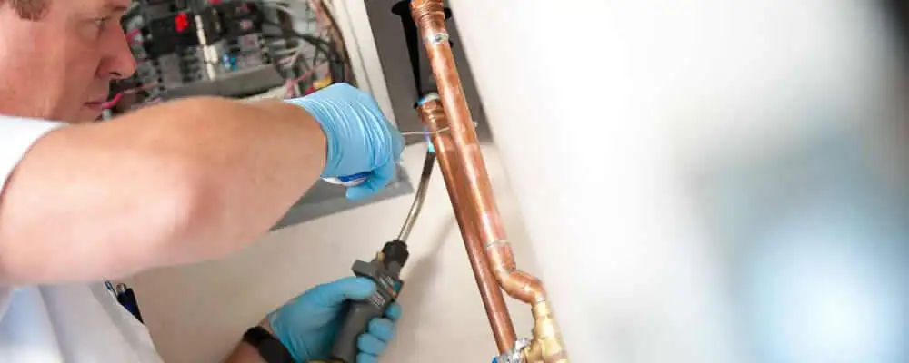 Water heater repair technician testing copper pipe connections and controls in Bradenton, FL